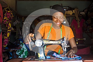 Portrait of a young african female tailor smiling while working with her sewing machine