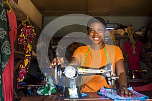 Portrait of a young african female tailor smiling while working with her sewing machine.