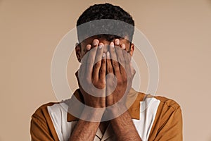 Portrait of young african man covering his face with hands