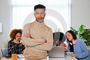 Portrait of young African man with his college mates studying in the background.