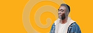 Portrait of young african man wearing eyeglasses looking away isolated on yellow background, blank copy space for advertising text