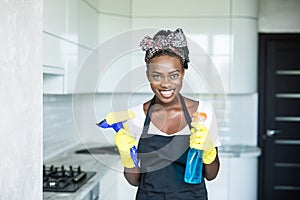 Portrait young african woman using spray to wipe windows glass