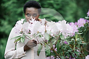 Portrait of young afro american woman surrounded purple flowers in park