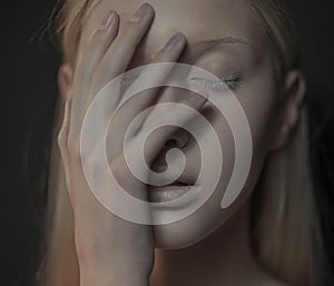 Young albino woman with closed eyes touches her face.