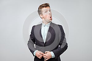 Portrait of young amazed man isolated on gray background