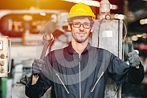 Portrait of young American happy worker enjoy happy smiling to work in a heavy industrial factory.Thumb up with big wrench