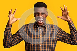 Portrait of young angry black man shouting with rage over yellow background