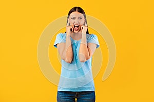 Portrait of young annoyed woman closing her ears with fingers