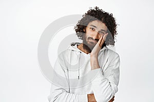 Portrait of young arab man looking sleepy and annoyed, bored of something, lean head on hand and staring unamused