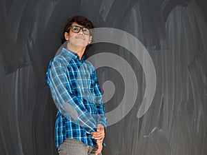 a portrait of a young Arab teenager standing in front of a school blackboard