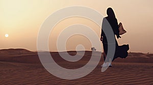 Portrait of a young Arab woman wearing traditional black clothing during beautiful sunset over the desert.