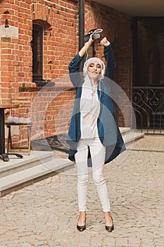 Portrait of young arabian muslim woman listening music with headphone and dancing. Feminism, woman independence and