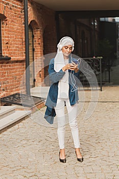 Portrait of young arabian muslim woman listening music with headphone and dancing. Feminism, woman independence and