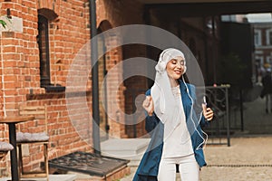 Portrait of young arabian muslim woman listening music with headphone and dancing. Feminism, woman independence and