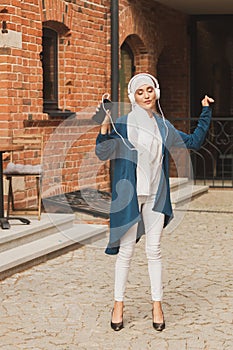 Portrait of young arabian muslim woman listening music with headphone and dancing. Feminism, woman independence and