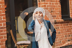 Portrait of young arabian muslim woman listening music with headphone and dancing. Feminism, woman independence and