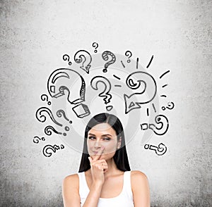 A portrait of a young artful brunette lady who is trying to find out a solution of some problem. The lady is in a white tank top.