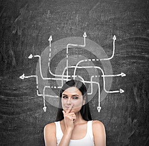 A portrait of a young artful brunette lady who is trying to find out the solution of some problem. The lady is in a white tank top