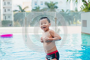 Portrait of Young asian boy kid child laughing in a swimming pool. Sunlight filter process