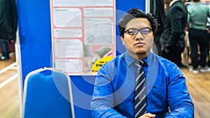 A portrait of a young Asian business man wearing a blue shirt shirt, black necktie and spectacles