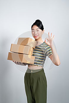 Portrait of young Asian business woman with boxes showing OK sign