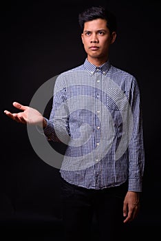 Portrait of young Asian businessman against black background