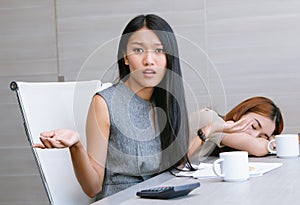 Portrait of young Asian businesswoman with arms out, shrugging her shoulders,saying: who cares, while workplace during work photo