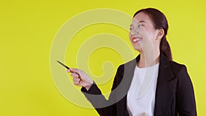 Portrait young asian businesswoman holding pen for presenting on yellow background, advertising and marketing.