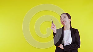 Portrait young asian businesswoman holding pen for presenting on yellow background, advertising and marketing.