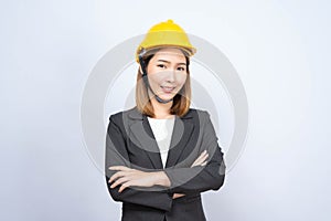 Portrait of Young Asian businesswoman wearing yellow safety-helmet in formal suit isolated on white background