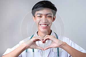 Portrait of young Asian doctor male showing heart shape gesture with fingers