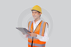 Portrait young asian engineer man wearing helmet looking document or report on clipboard isolated.