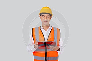 Portrait young asian engineer man wearing helmet looking document or report on clipboard isolated.