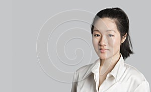 Portrait of a young Asian female doctor over gray background