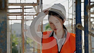 Portrait, young Asian female engineer standing proudly smiling at her work site.