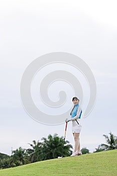 Portrait of young asian female golfer holding the golf club at the course