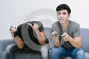 Portrait of young Asian gay couple playing video games, using controllers and excited holding console playing game together while