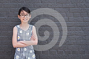 Portrait of young Asian girl against black brick wall