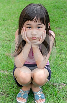 Portrait of a Young Asian Girl Crouching on Grass