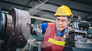 Portrait of a young Asian industrial worker using measuring tool on the machine.