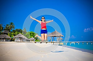 Portrait of young asian looking woman jumping happy at beautiful tropical beach at Maldives