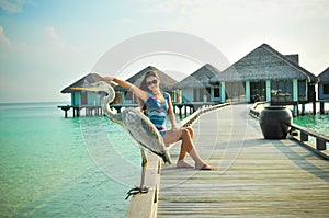 Portrait of young asian looking woman pretending touching a bird at tropical beach at Maldives
