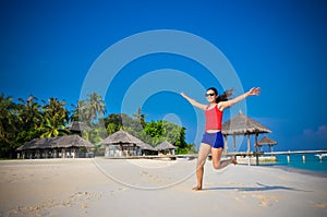 Portrait of young asian looking woman rising up hands at beautiful tropical beach at Maldives