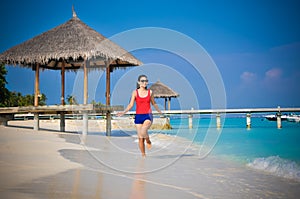 Portrait of young asian looking woman running at beautiful tropical beach at Maldives