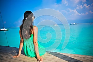 Portrait of young asian looking woman sitting the hut in green dress at beautiful tropical beach at Maldives