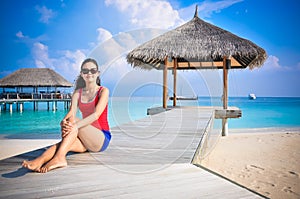 Portrait of young asian looking woman sitting near hut at beautiful tropical beach at Maldives