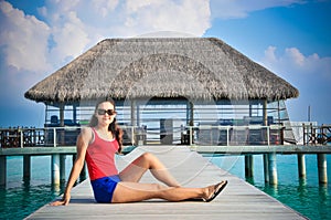 Portrait of young asian looking woman sitting near restaurant at beautiful tropical beach at Maldives