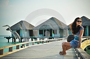 Portrait of young asian looking woman sitting next to bird at tropical beach at Maldives