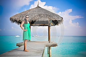 Portrait of young asian looking woman standing near hut in green dress at beautiful tropical beach.Maldives.