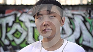Portrait of a young Asian man against a background of street graffiti. Korean or Japanese teenager, youth. Modern youth